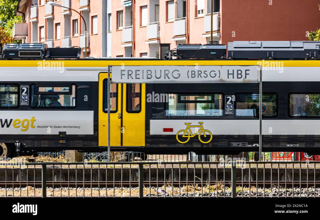Ein Schild der Freiburger Hauptbahnhof, dahinter fährt ein Zug der deutsche Bahn durch. (Freiburg im Breisgau, Allemagne, 07.08.2022) Banque D'Images