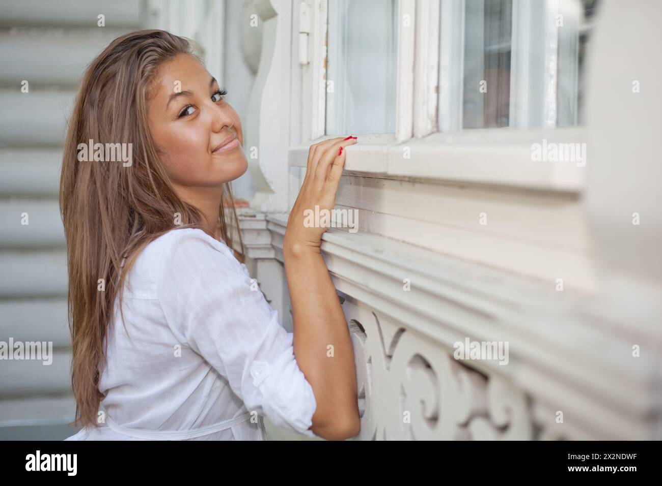 Belle fille penchée à la maison de village en bois Banque D'Images