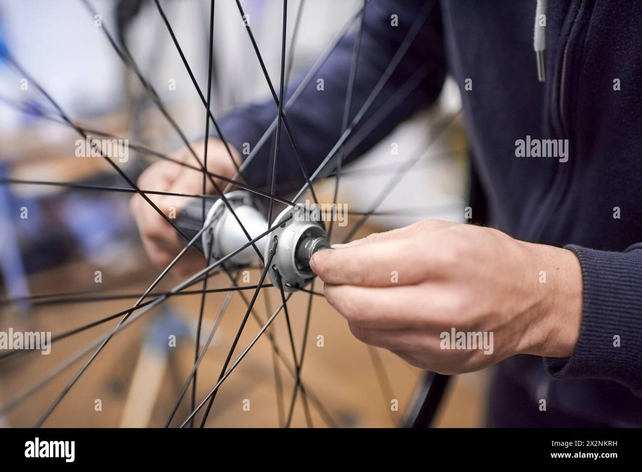 Homme méconnaissable assemblant un essieu de roue de vélo après l'avoir démonté pour le nettoyage et le graissage dans le cadre d'un service d'entretien de vélo. De vraies personnes Banque D'Images