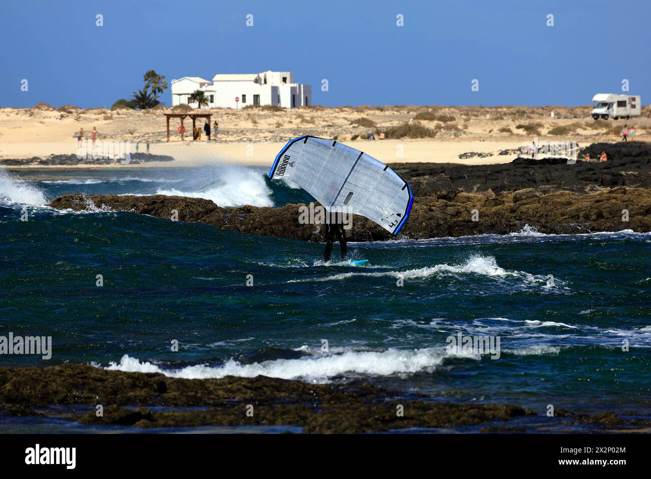 Homme plus âgé avec planche de feuille et voile à une plage rocheuse, El Cotillo, Fuerteventura, Îles Canaries, Espagne, Europe. Prise en février 2024 Banque D'Images