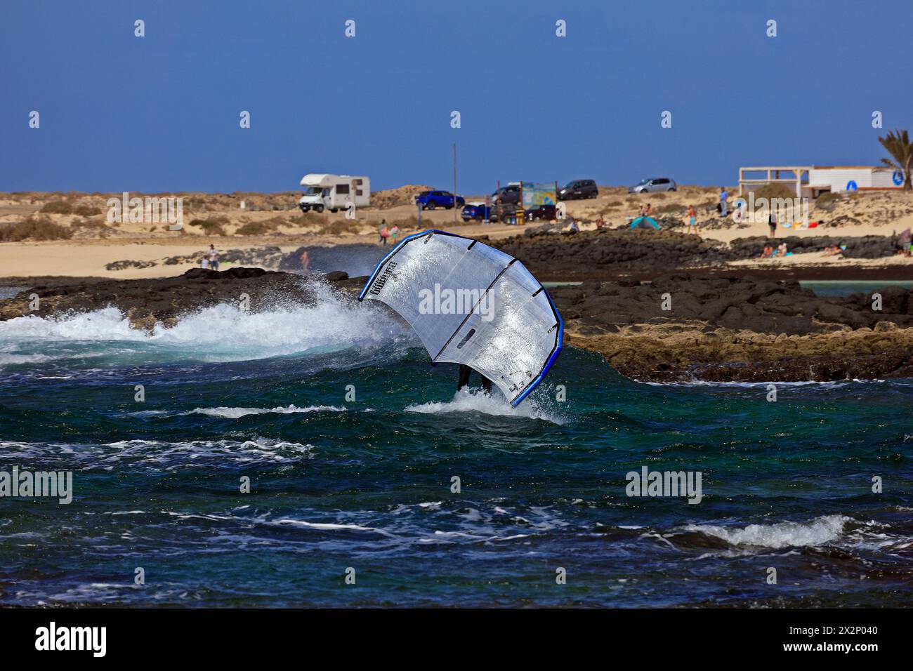 Homme plus âgé avec planche de feuille et voile à une plage rocheuse, El Cotillo, Fuerteventura, Îles Canaries, Espagne, Europe. Prise en février 2024 Banque D'Images