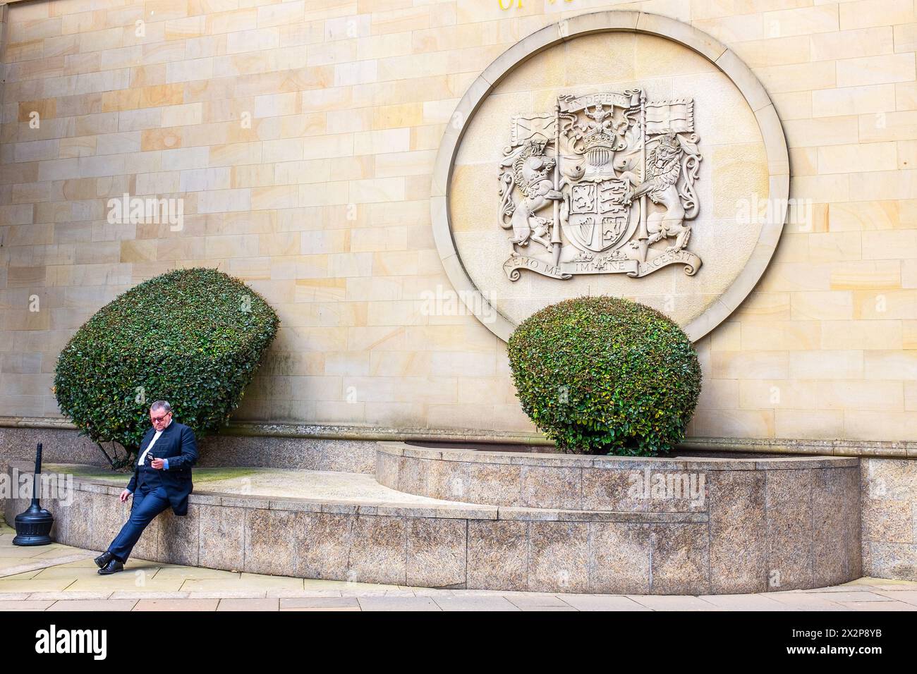 Avocat assis au mur devant la haute Cour de justice, avec le logo de la Cour au-dessus, Saltmarket, Glasgow, Écosse, Royaume-Uni Banque D'Images