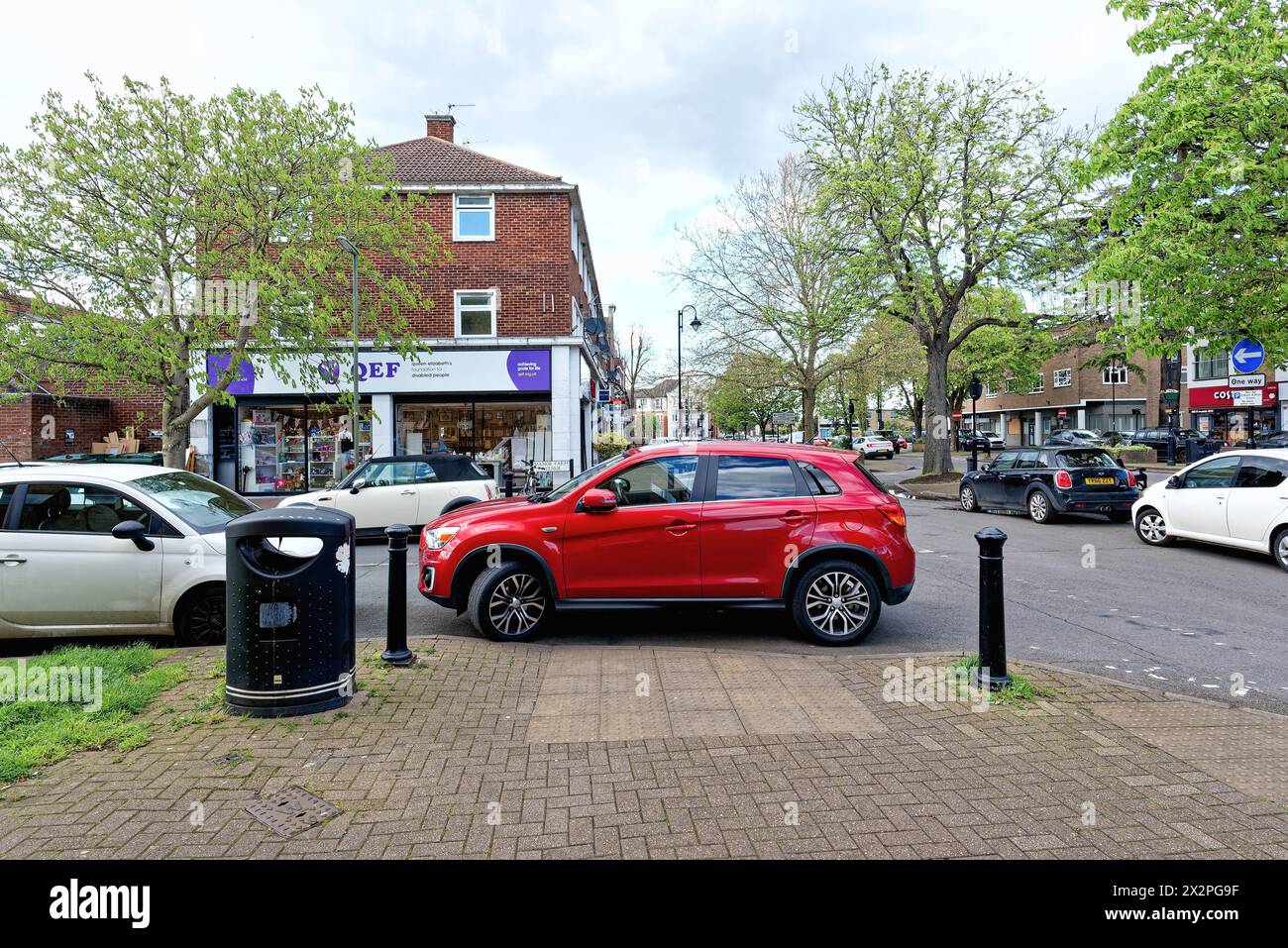 Une voiture mal garée obstruant un trottoir tombé sur un trottoir dans une grande rue de banlieue, Shepperton Surrey Angleterre Banque D'Images