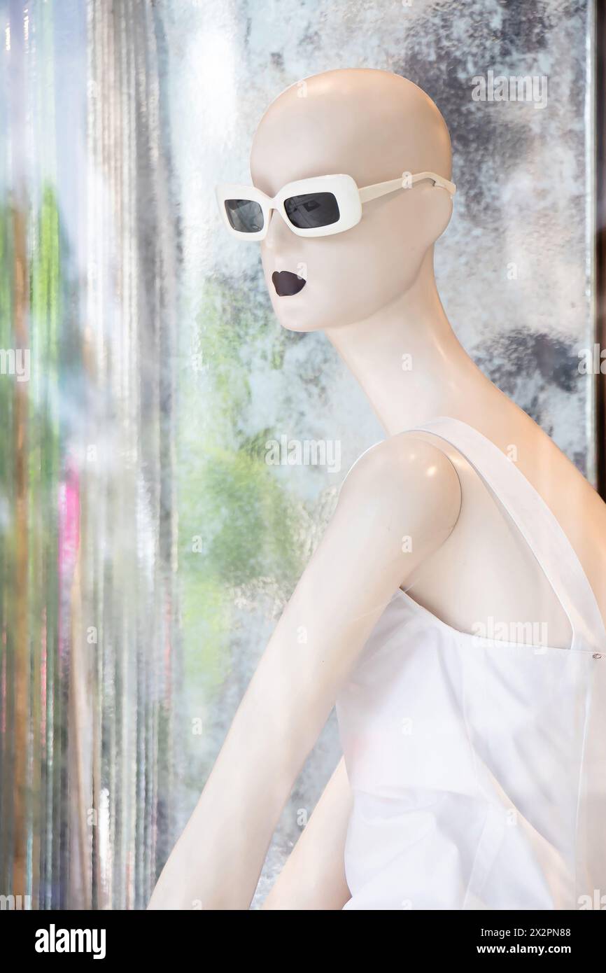 Belgrade, Serbie - 3 avril 2024 : une poupée mannequin chauve en robe blanche avec des reflets dans la vitrine du magasin Max Mara Banque D'Images