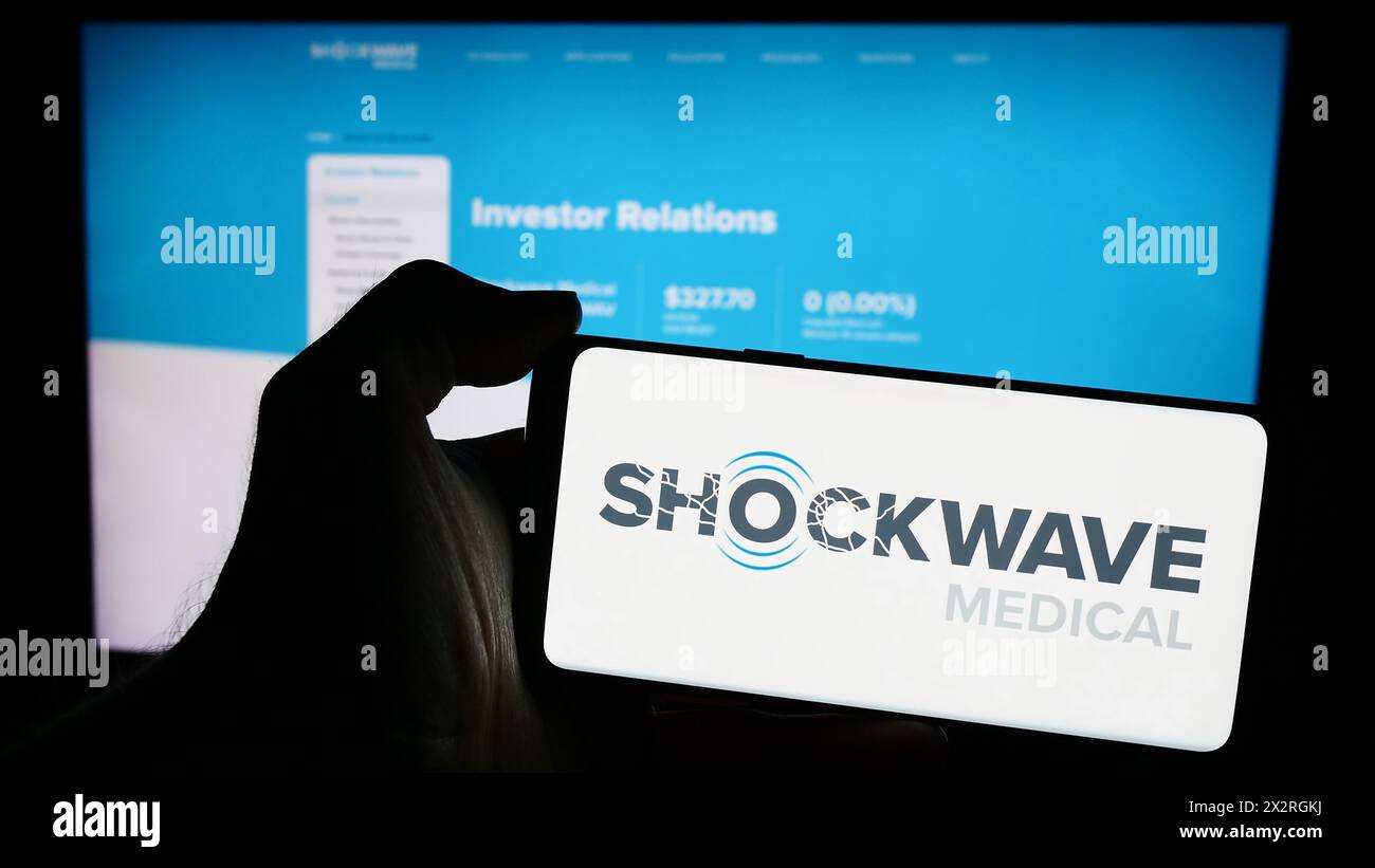 Personne tenant un smartphone avec le logo de la société américaine de maladies cardiovasculaires Shockwave Medical Inc en face du site Web. Concentrez-vous sur l'affichage du téléphone. Banque D'Images