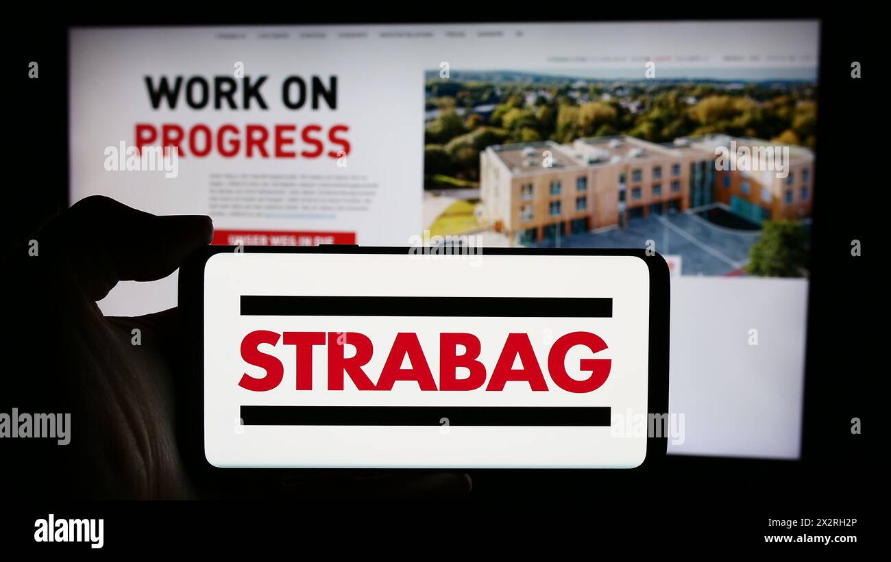 Personne tenant un smartphone avec le logo de l'entreprise de construction autrichienne Strabag se en face du site Web. Concentrez-vous sur l'affichage du téléphone. Banque D'Images