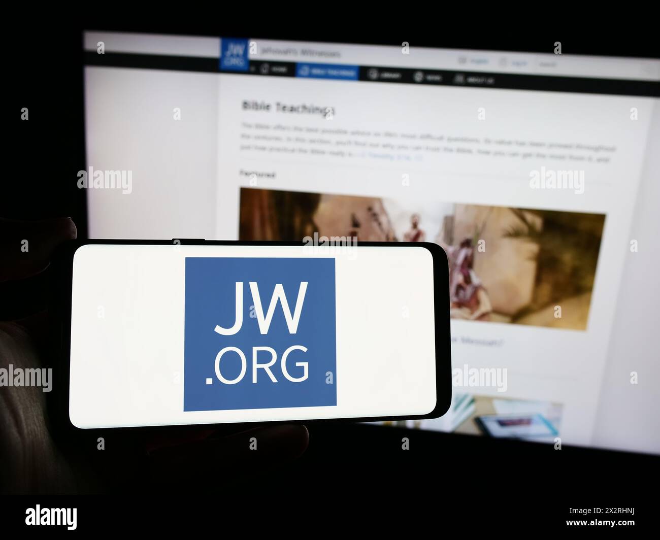 Personne tenant un smartphone avec le logo de l'organisation religieuse témoins de Jéhovah devant le site Web. Concentrez-vous sur l'affichage du téléphone. Banque D'Images