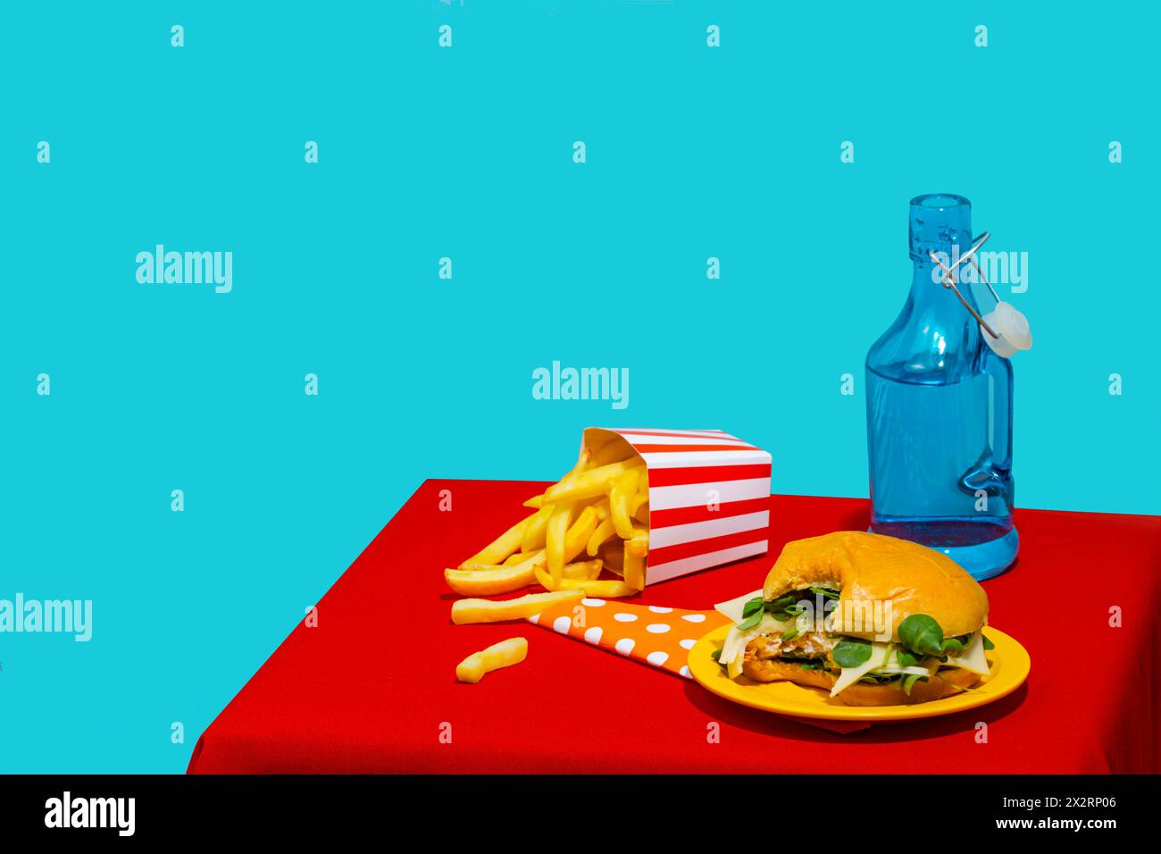 Morsure prise de hamburger près de frites et bouteille de soda sur fond bleu Banque D'Images
