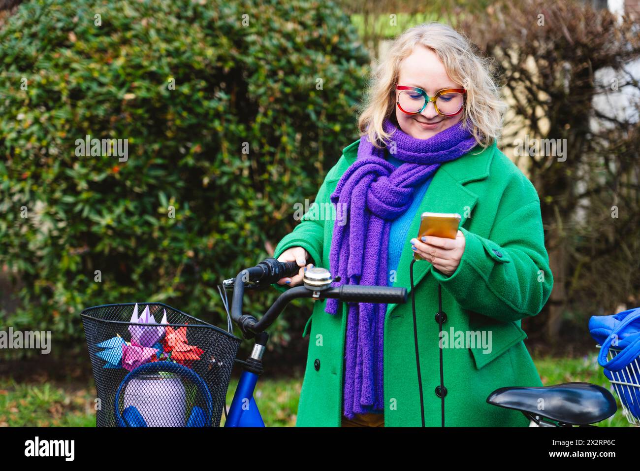 Femme utilisant un téléphone intelligent debout avec un vélo au parc Banque D'Images