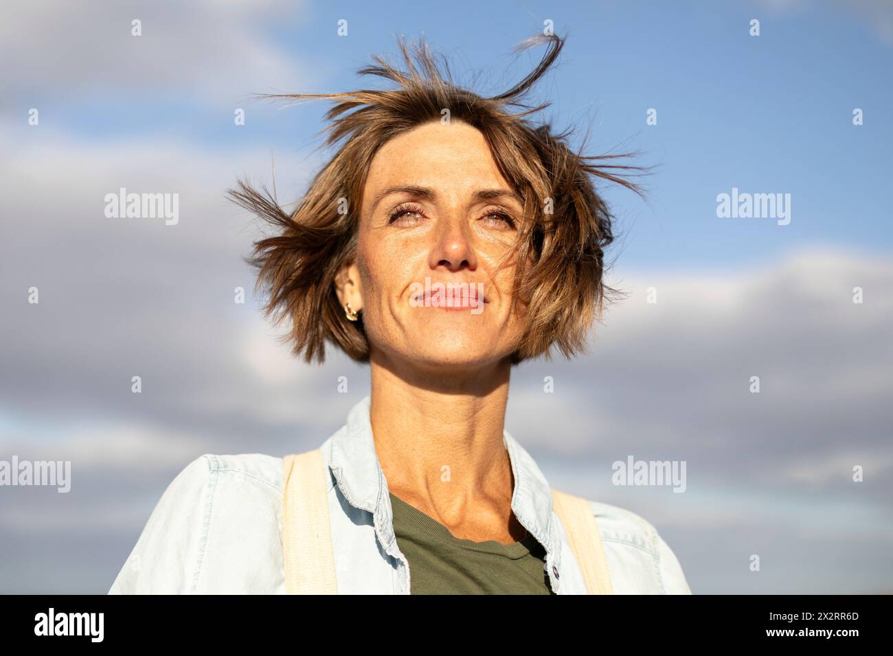 Femme souriante avec les cheveux courts sous le ciel Banque D'Images