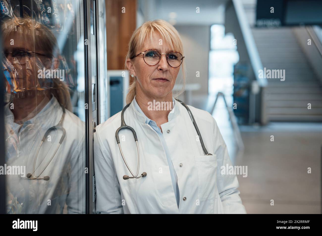 Médecin mûr s'appuyant sur le distributeur automatique à l'hôpital Banque D'Images