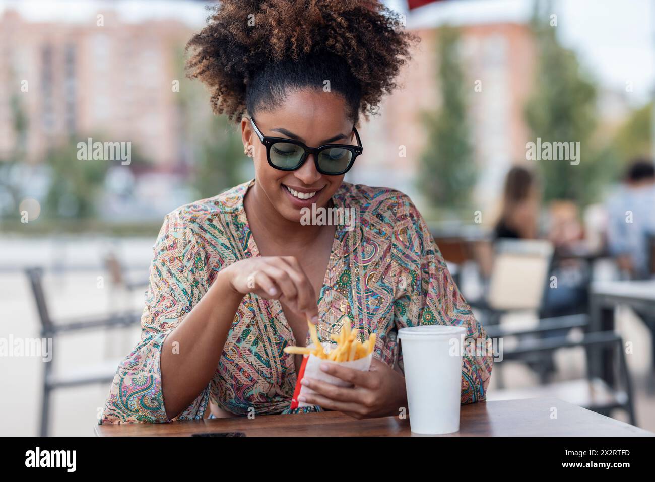 Femme heureuse mangeant des frites au café trottoir Banque D'Images