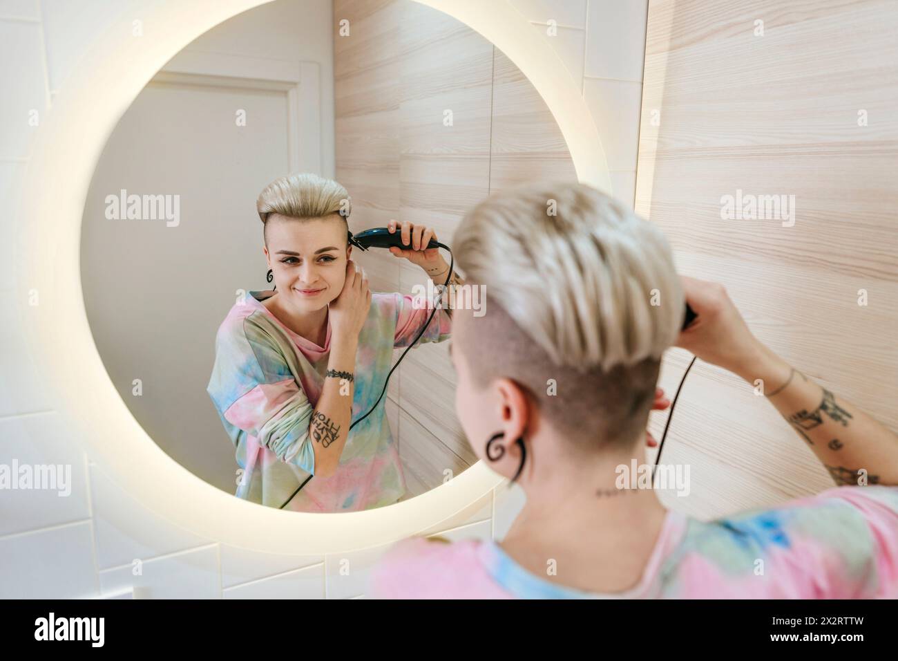 Jeune femme hipster taillant les cheveux dans la salle de bain à la maison Banque D'Images