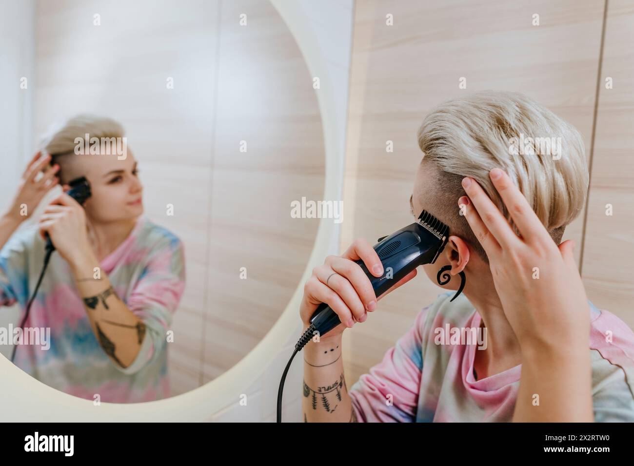 Femme taillant les cheveux à l'aide d'un rasoir électrique dans la salle de bain à la maison Banque D'Images