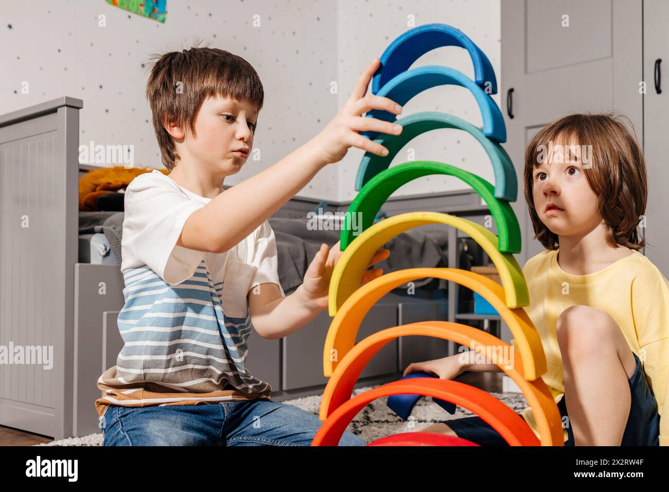 Frères construisant une pyramide avec des jouets multicolores arc-en-ciel à la maison Banque D'Images