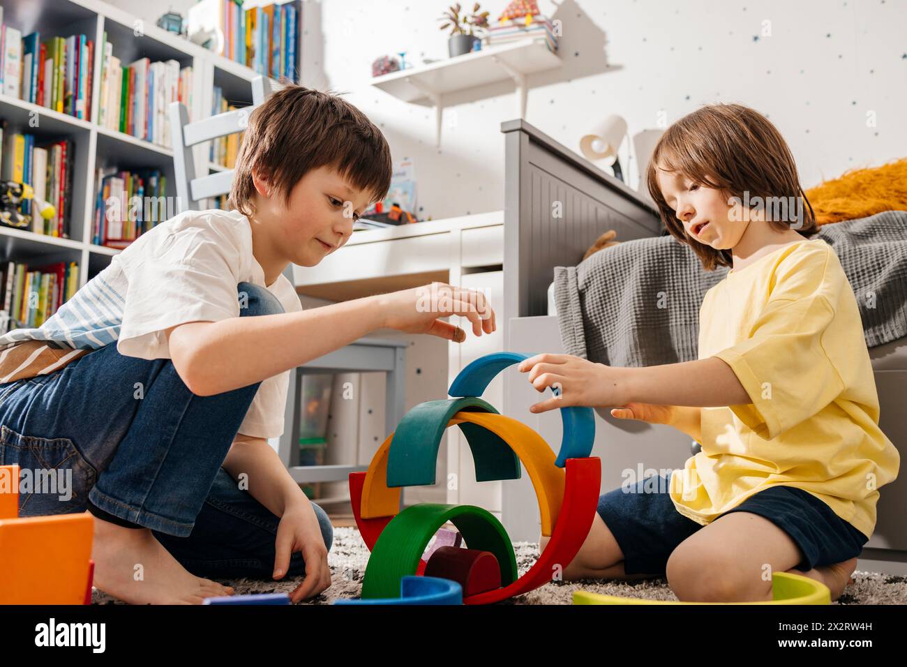 Garçons jouant avec des jouets multicolores en bois à la maison Banque D'Images