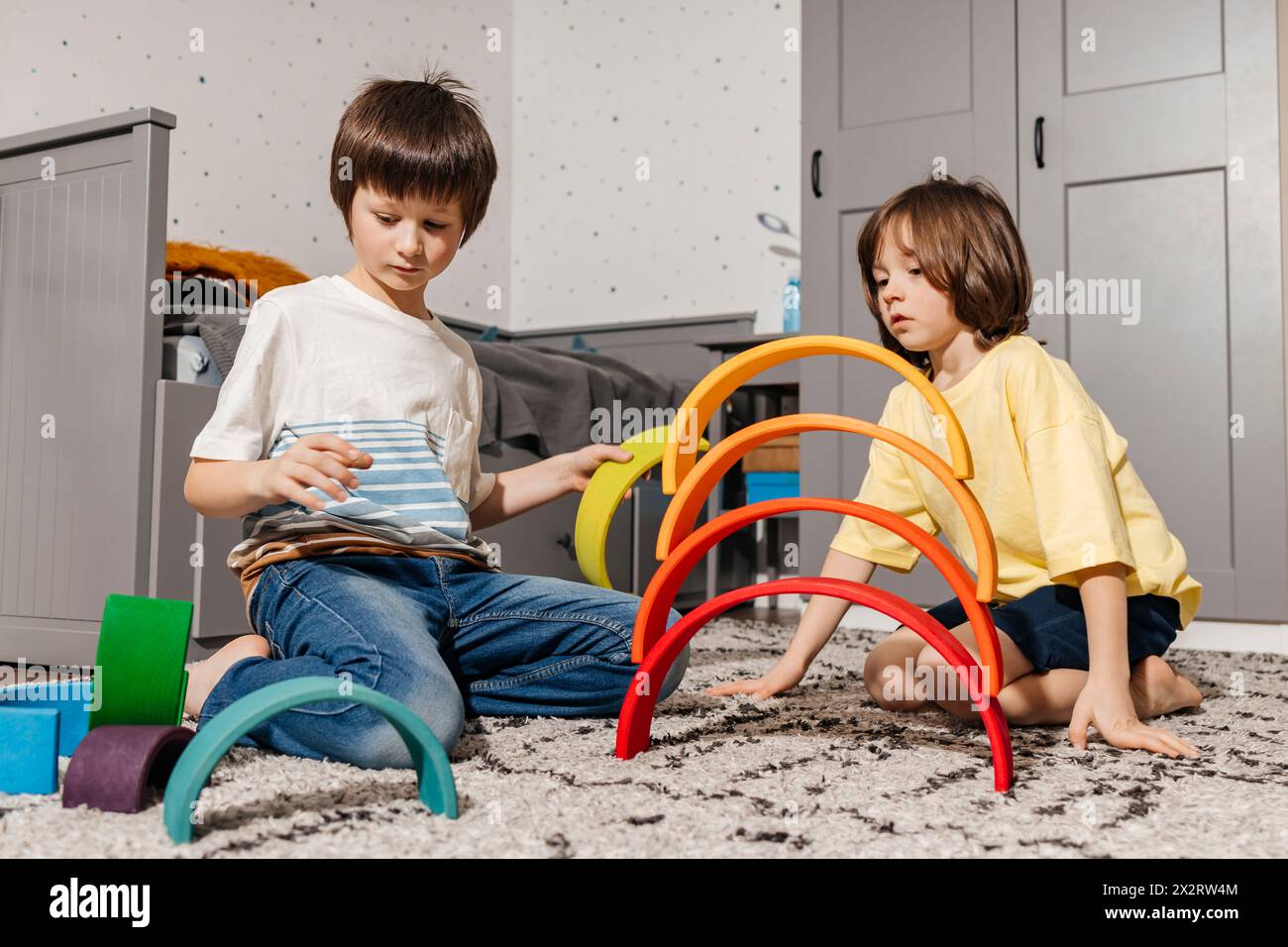 Garçons construisant pyramide avec des jouets multicolores arc-en-ciel à la maison Banque D'Images