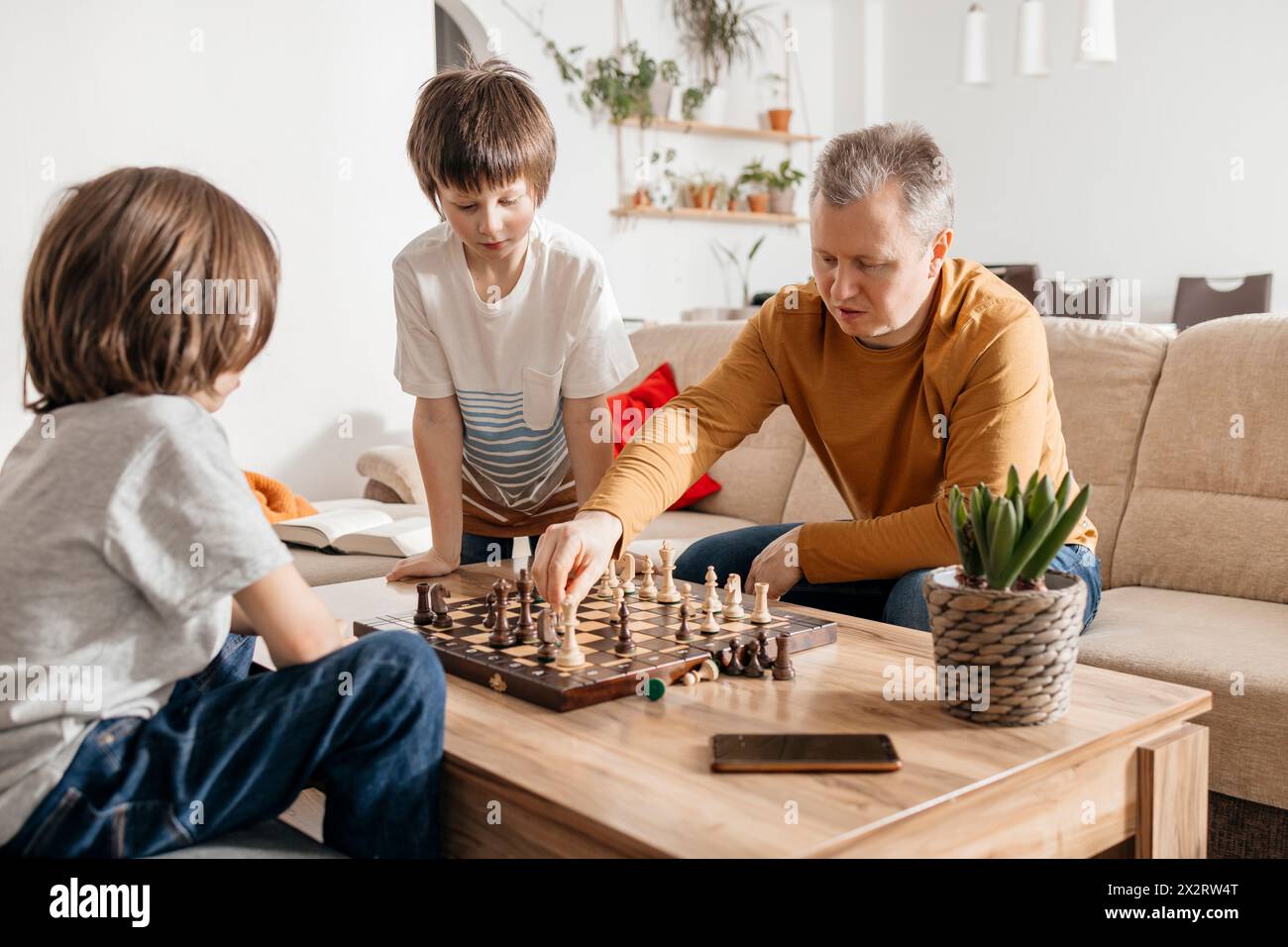 Père jouant aux échecs avec les enfants à la maison Banque D'Images