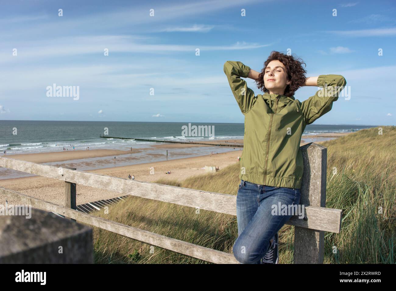 Belle femme avec les mains derrière la tête appuyée sur la balustrade à la plage Banque D'Images