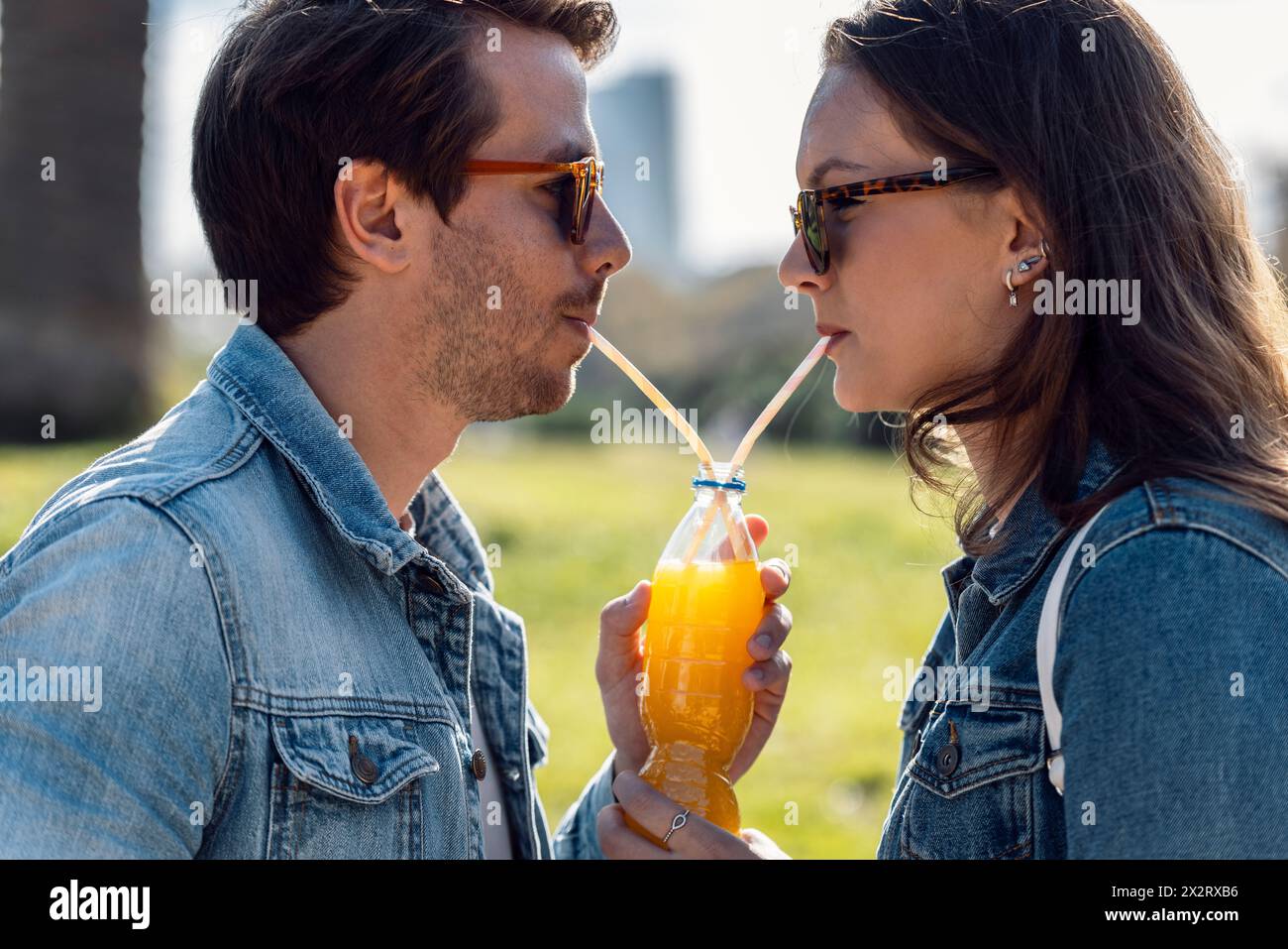 Couple portant des lunettes de soleil et buvant du jus à travers de la paille Banque D'Images