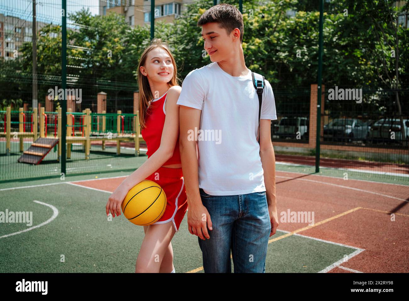 Joueur de basket-ball souriant debout avec un ami dans la cour de l'école Banque D'Images