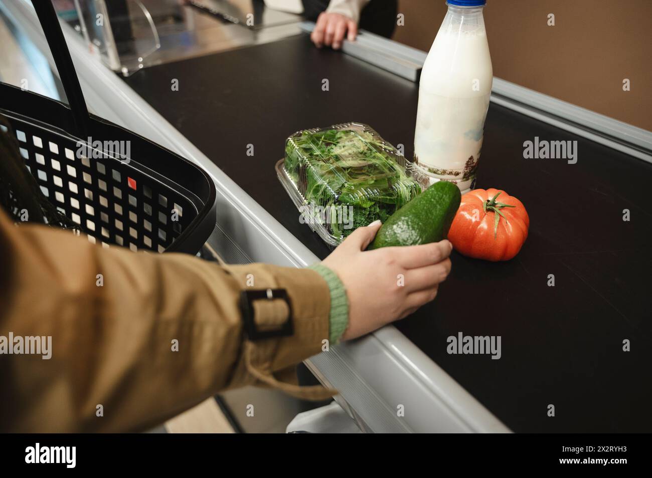 Femme mettant l'épicerie sur la bande transporteuse pour la caisse au supermarché Banque D'Images