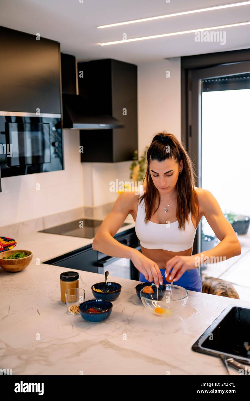 Femme cassant des œufs dans un bol à la maison Banque D'Images