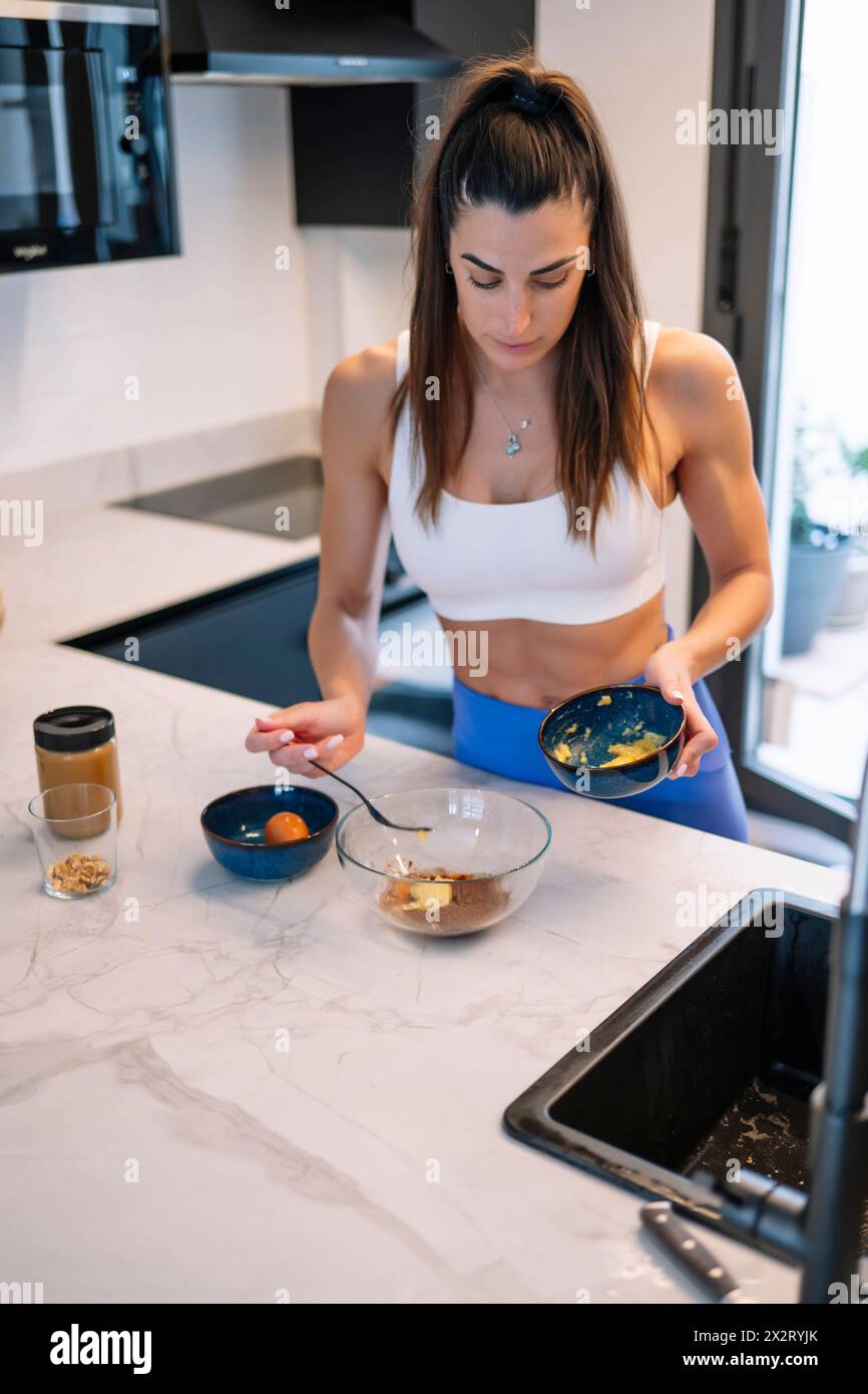 Femme musclée préparant le désert dans la cuisine à la maison Banque D'Images