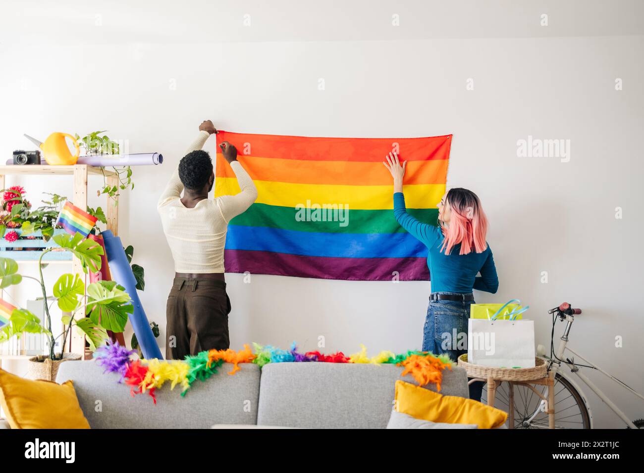 Jeune personne non binaire et ami décorant la maison pour la fête gay Pride Banque D'Images