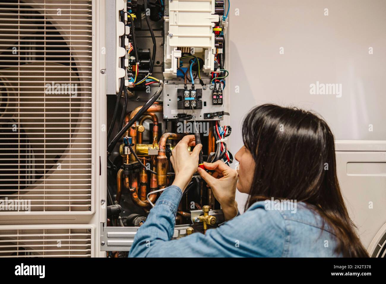 Technicien féminin examinant l'unité AC Banque D'Images