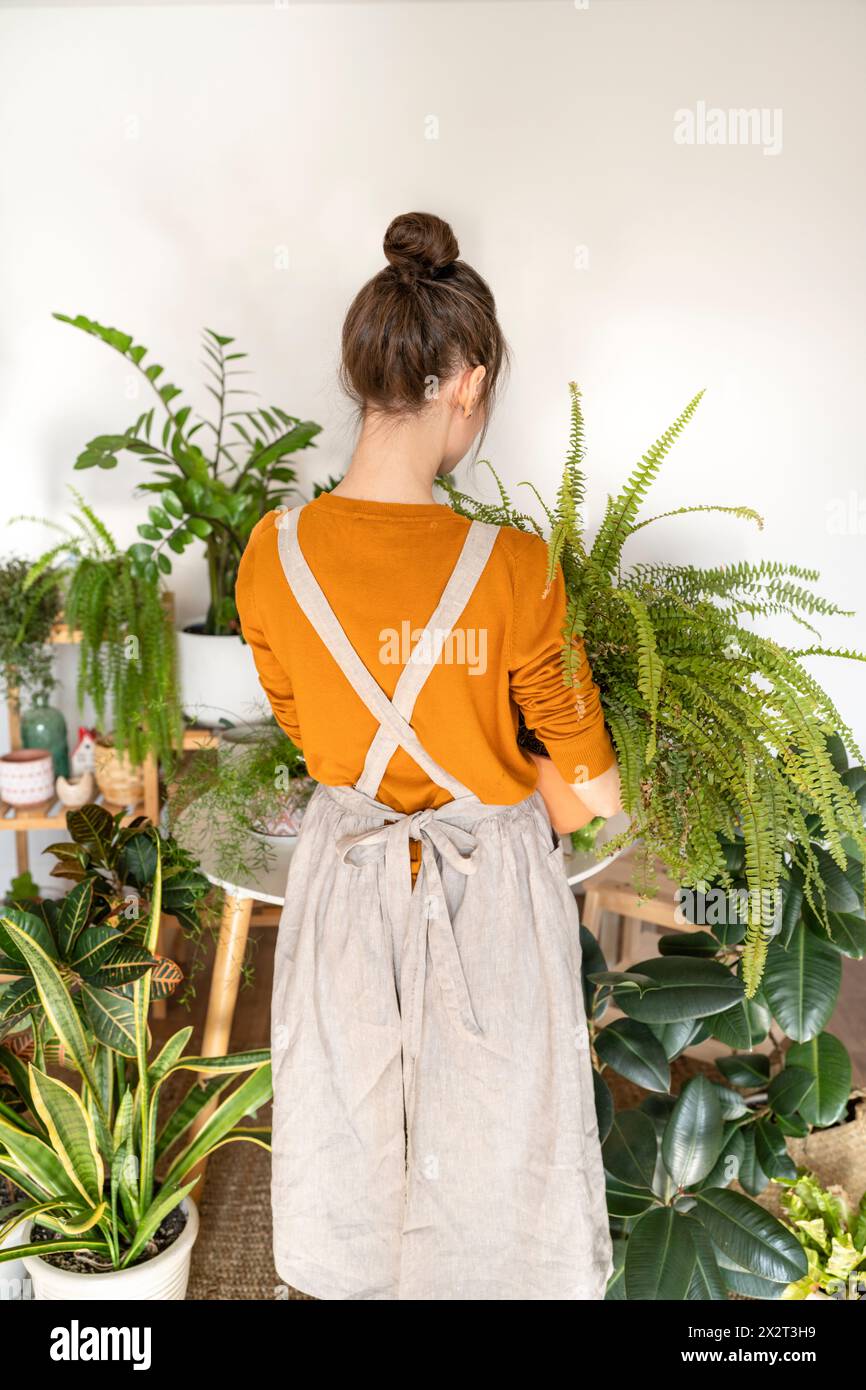 Femme avec chignon de cheveux debout au milieu des plantes à la pépinière Banque D'Images