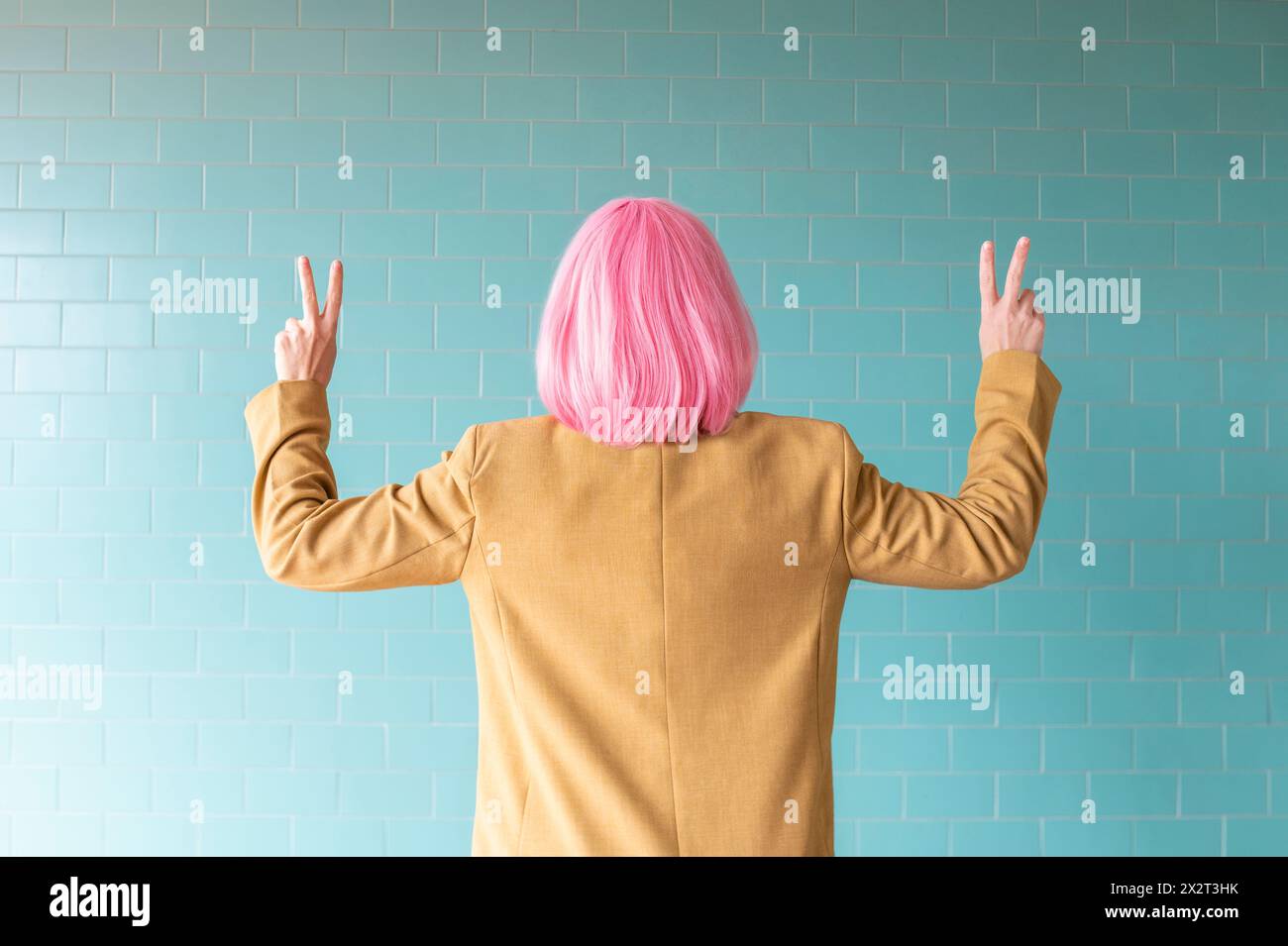Femme gestuelle signe de paix près du mur turquoise Banque D'Images