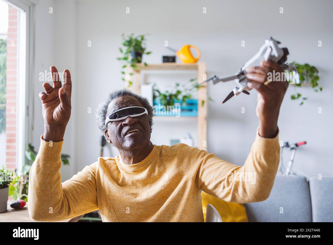 Homme senior dans les lunettes VR apprenant à faire fonctionner le drone à la maison Banque D'Images