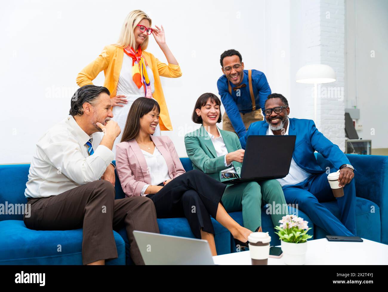 Heureuse femme d'affaires travaillant sur ordinateur portable avec des collègues assis sur le canapé au bureau Banque D'Images