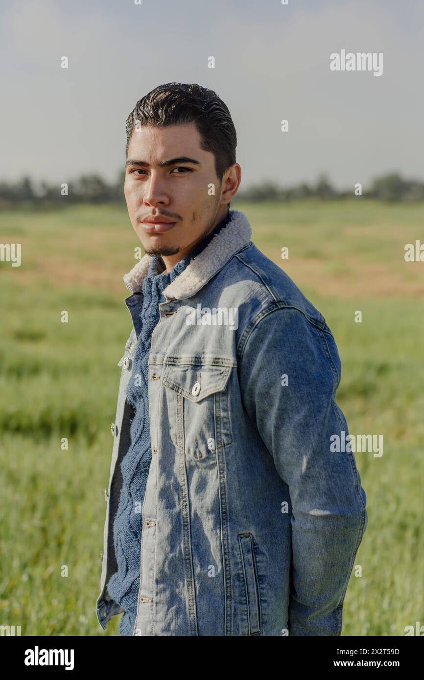 Jeune homme confiant en veste denim debout sur la prairie Banque D'Images