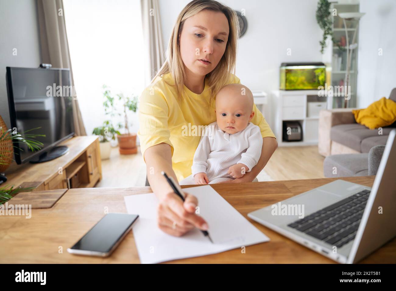 Femme d'affaires écrivant sur papier assis avec son fils à table Banque D'Images