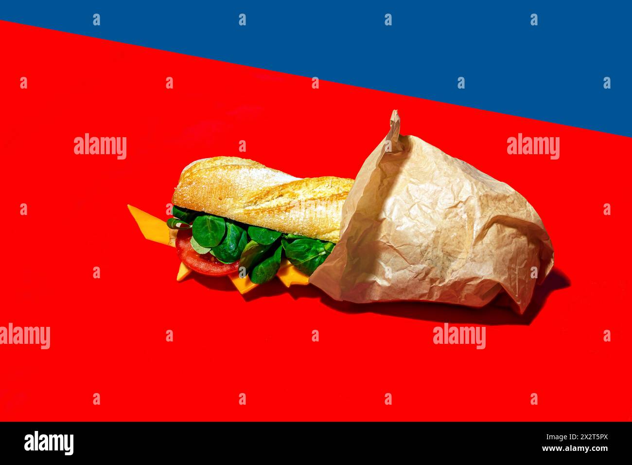 Sandwich au fromage enveloppé dans du papier sur fond rouge Banque D'Images