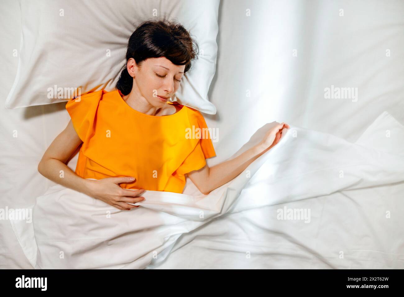 Femme en t-shirt jaune dormant sur le lit à la maison Banque D'Images