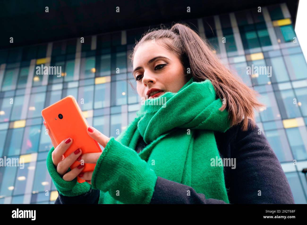 Belle femme utilisant un téléphone intelligent en face du bâtiment Banque D'Images