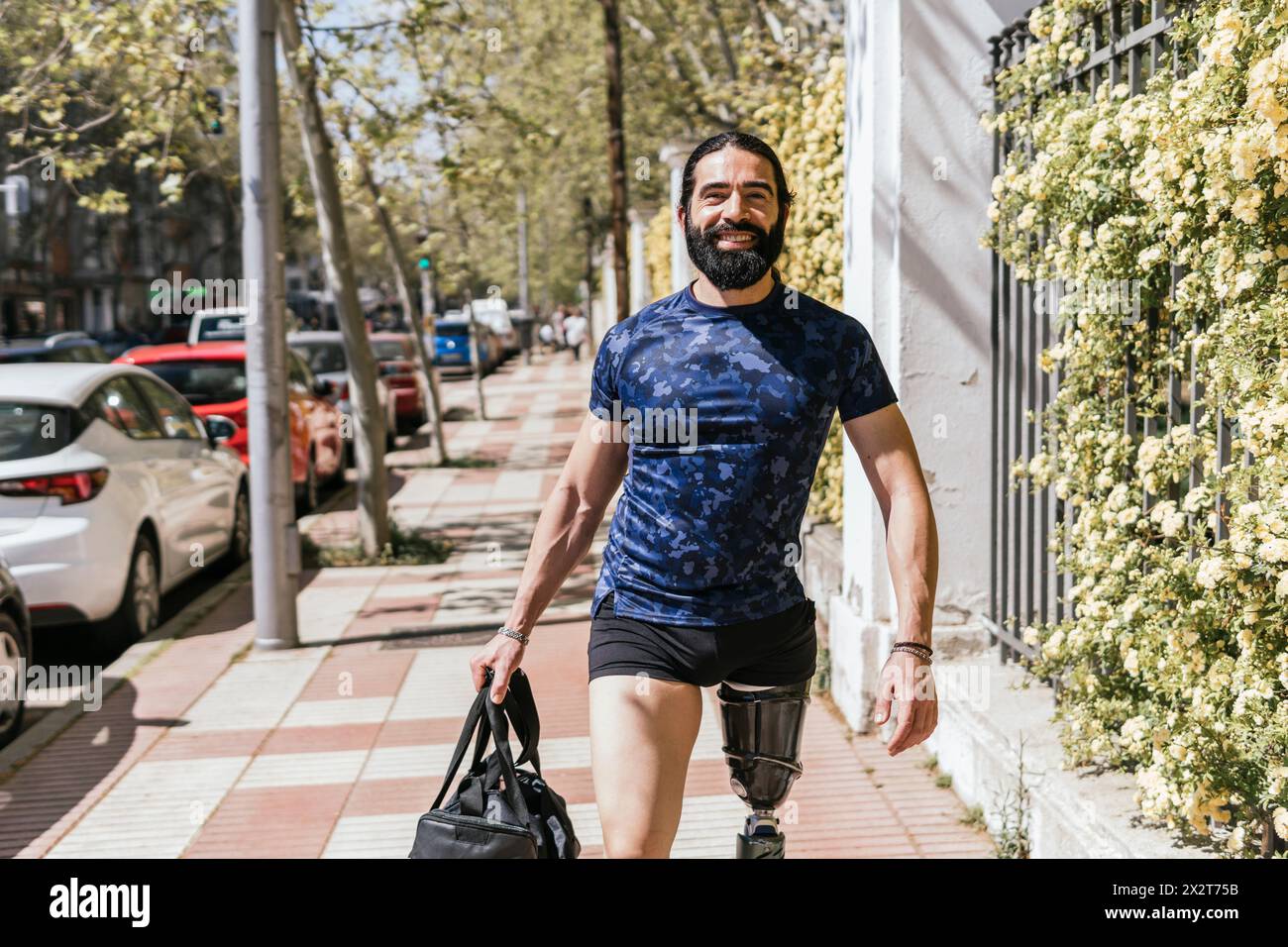 Athlète souriant avec une jambe prothétique marchant sur le trottoir Banque D'Images