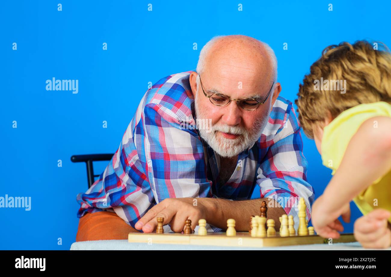 Grand-père apprenant à petit-fils à jouer aux échecs. Enfants et jeux de logique de société. Grand-père et petit-fils jouant aux échecs ensemble à la maison. Passe-temps et loisirs Banque D'Images