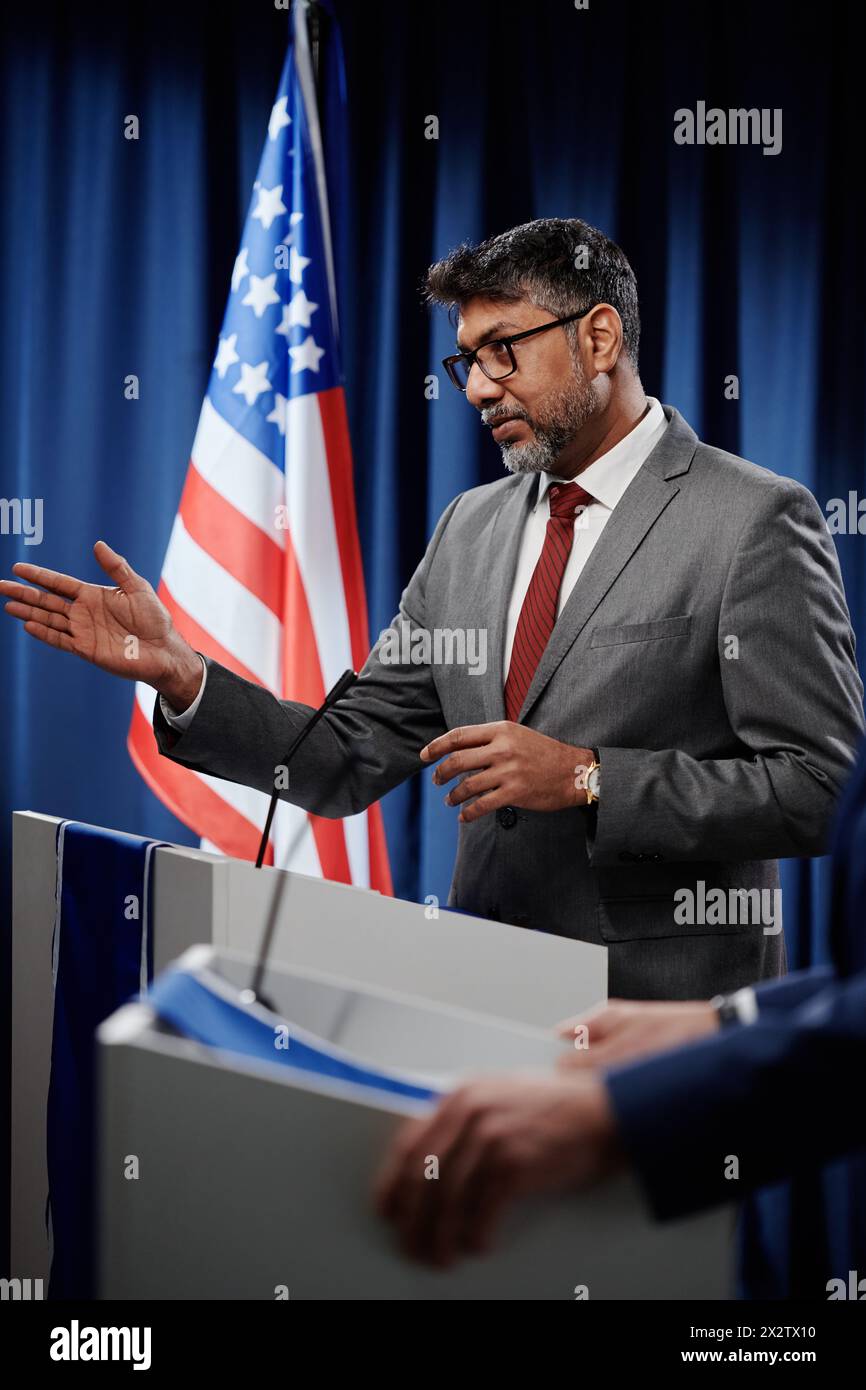 Confiant, mûr, délégué masculin multiethnique en habillement officiel prononçant un discours politique à la conférence pour les pays inclus dans le g7 Banque D'Images