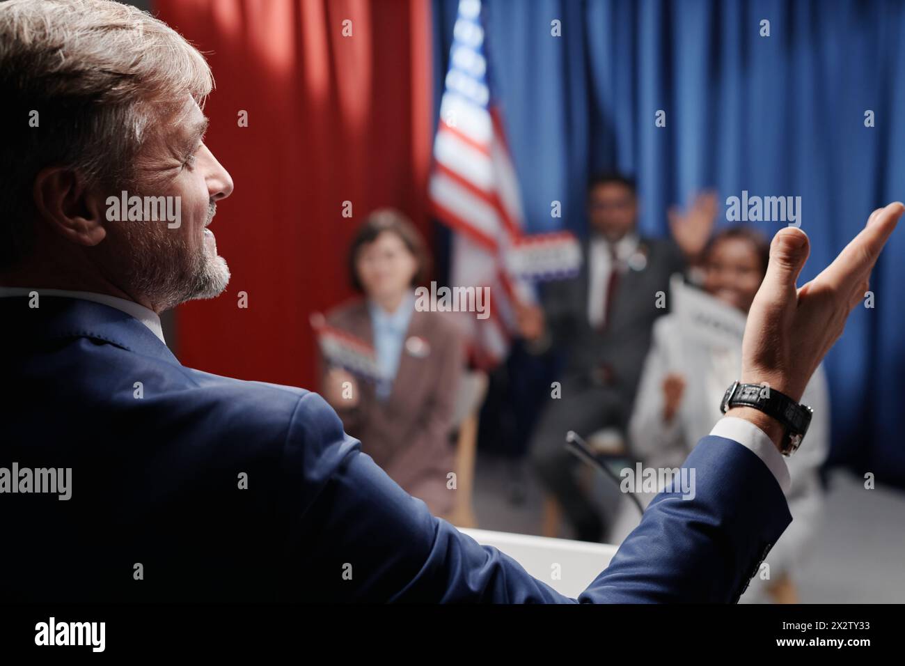 Une partie de la vue arrière d'un leader politique mature et confiant en vêtements de forme gesticulant devant l'électorat tout en faisant un discours Banque D'Images