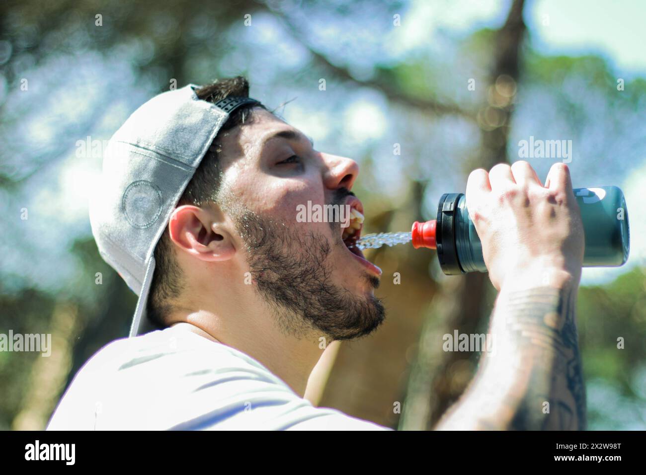 Sport rafraîchissant : jeune homme s'hydratant au milieu de la splendeur de la nature Banque D'Images