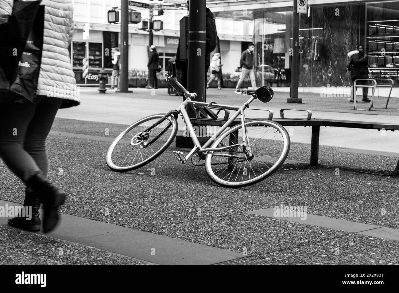 Vancouver, Canada - 23 février 2024 : photo en noir et blanc d'un vélo penché sur un banc sur le trottoir de la rue Granville Banque D'Images