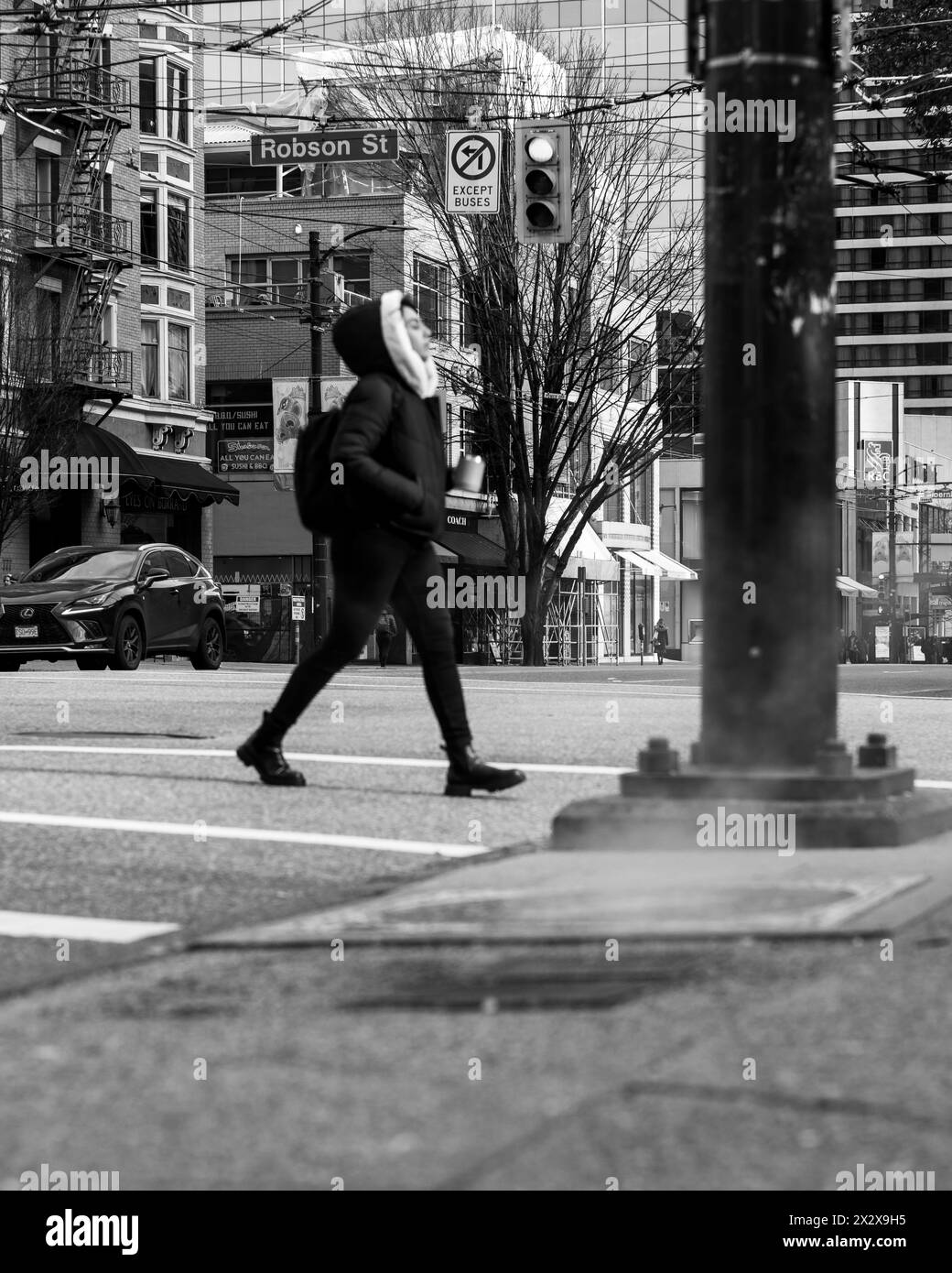 Une vue en noir et blanc à angle bas de l'intersection des rues Robson et Burrard avec un échappement de vapeur sur le trottoir et une personne marchant. Banque D'Images