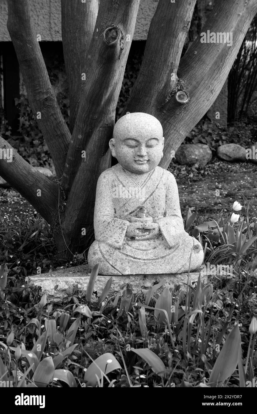 Sculpture en granit d'un Bouddha et d'un lapin assis sous un arbre, noir et blanc Banque D'Images