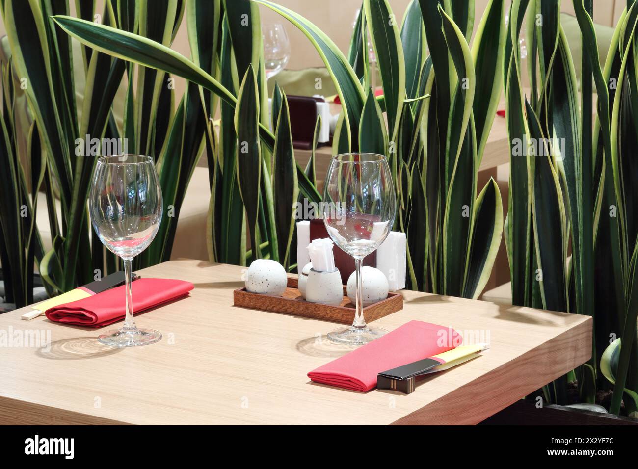 Verres vides sur la table carrée, serviettes rouges et feuilles vertes dans le restaurant japonais. Banque D'Images