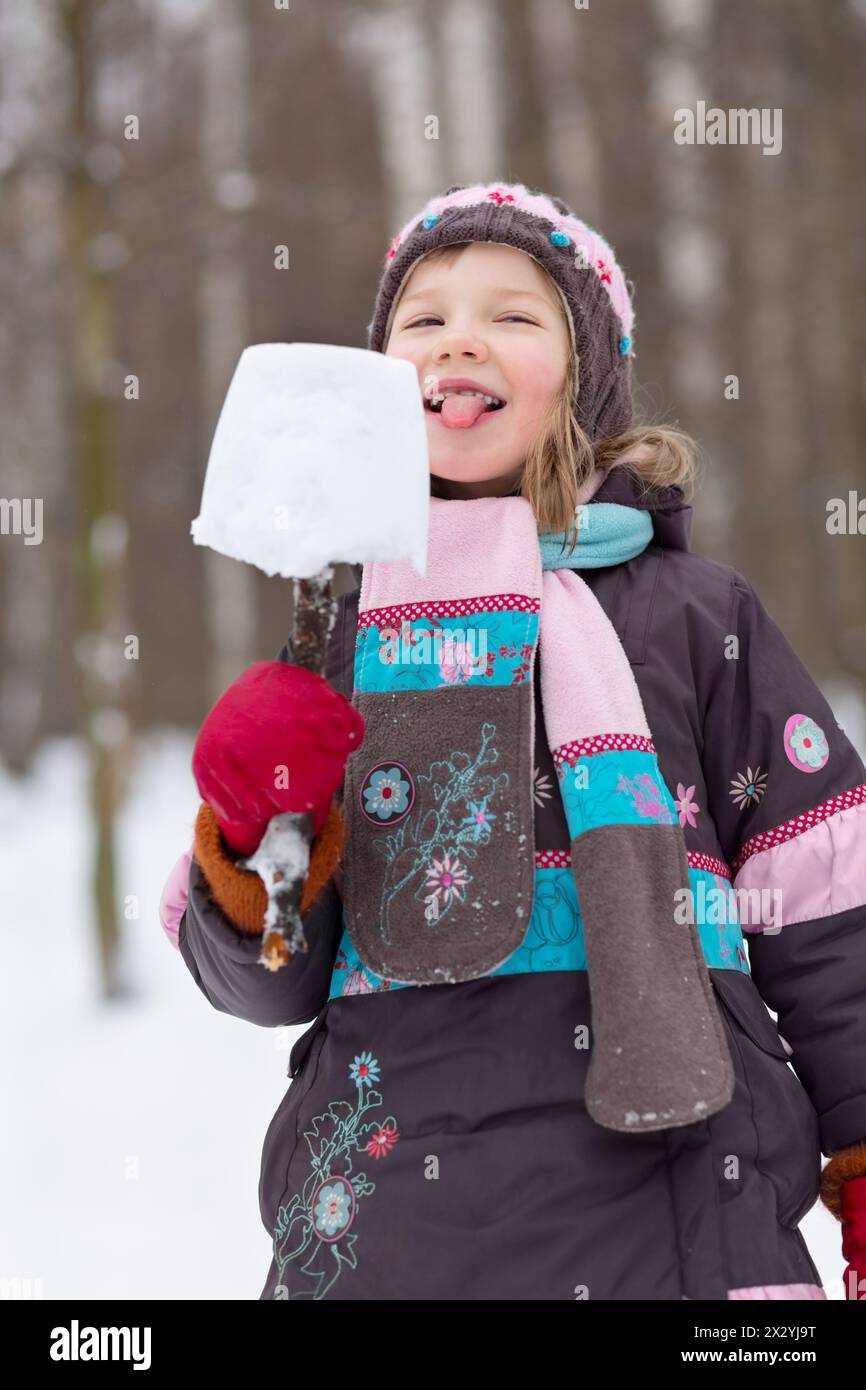 Fille mange eskimo fait de morceau de neige et de branche cassée dans le parc d'hiver Banque D'Images