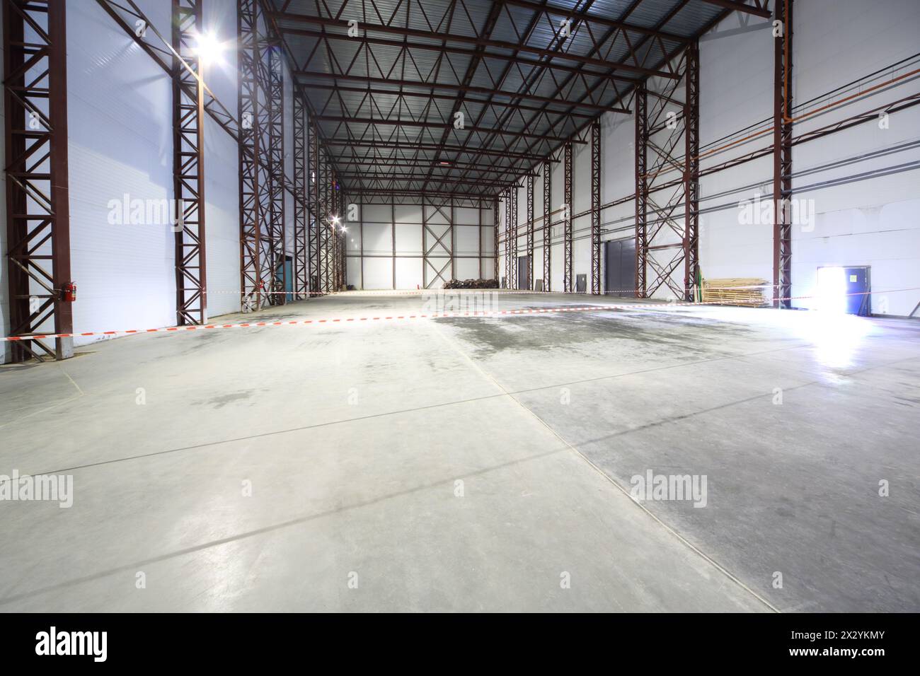 Grand hangar vide léger avec plancher en béton et entrées pour les gros camions. Banque D'Images